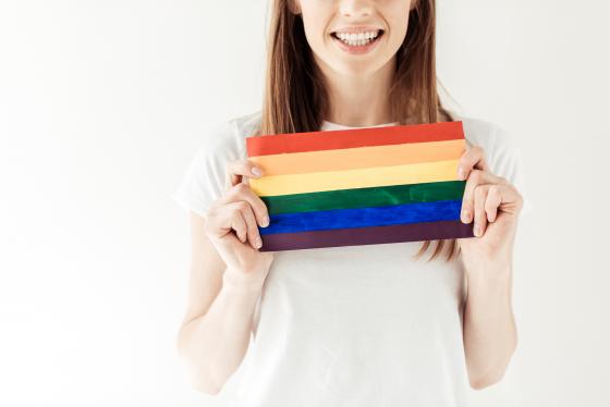 a woman is holding a LGBT flag